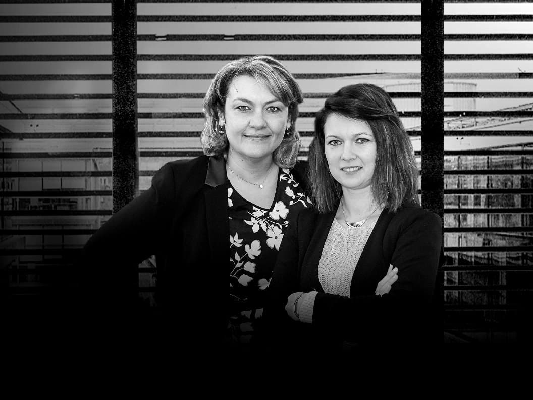 Sabrina Abbey et Amandine Hergault, côte à côte devant des lames horizontales, en noir et blanc